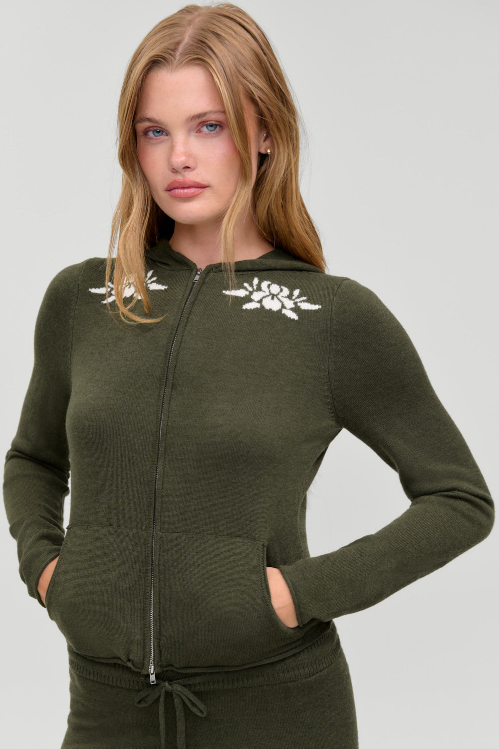 Calvin knit zip up hoodie in Alpine Flower, olive knit with cream floral intarsia, front view on model