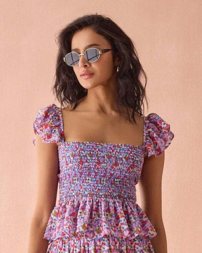 Woman wearing a colorful floral dress against a pink background