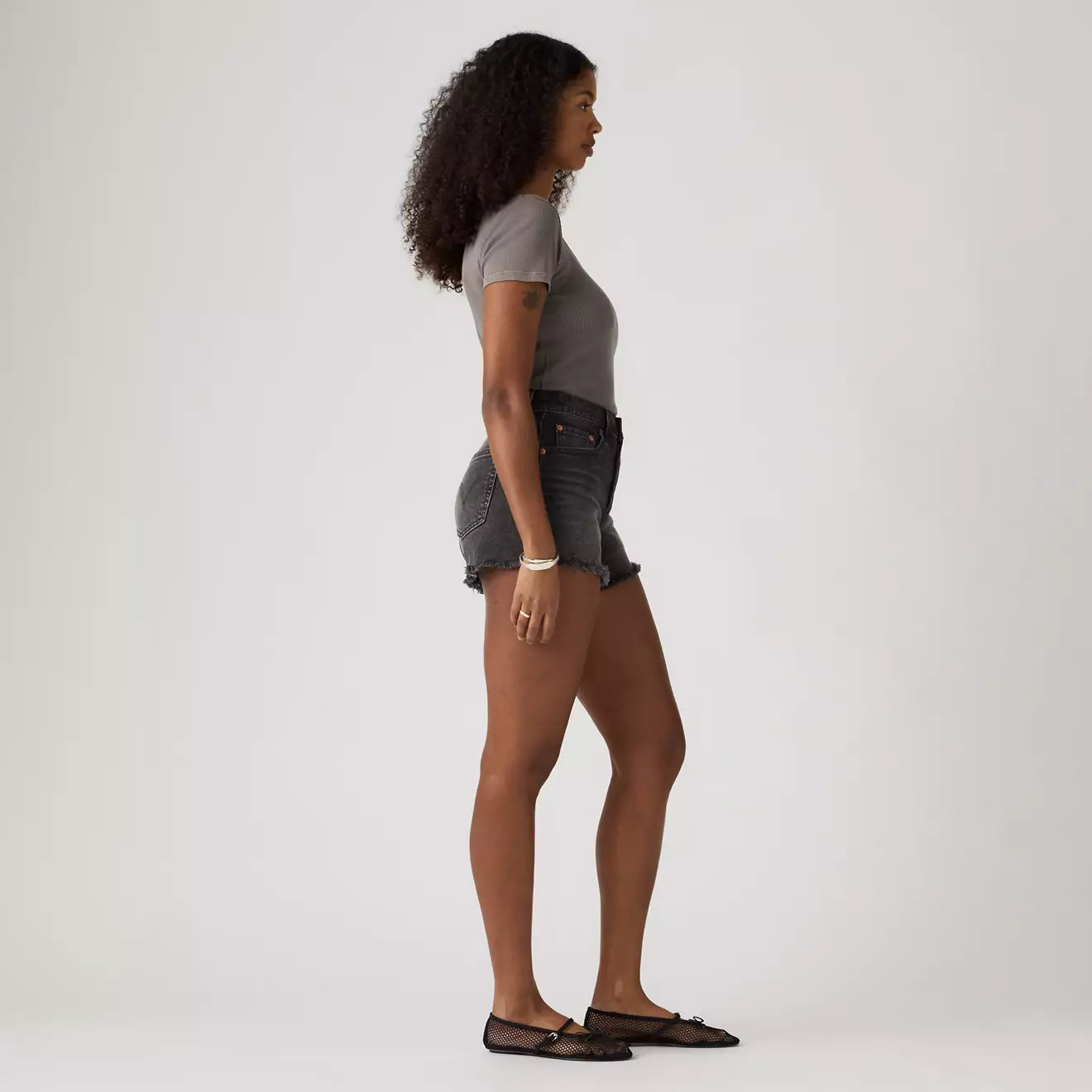 Woman wearing a gray t-shirt and denim Levi shorts on a white background