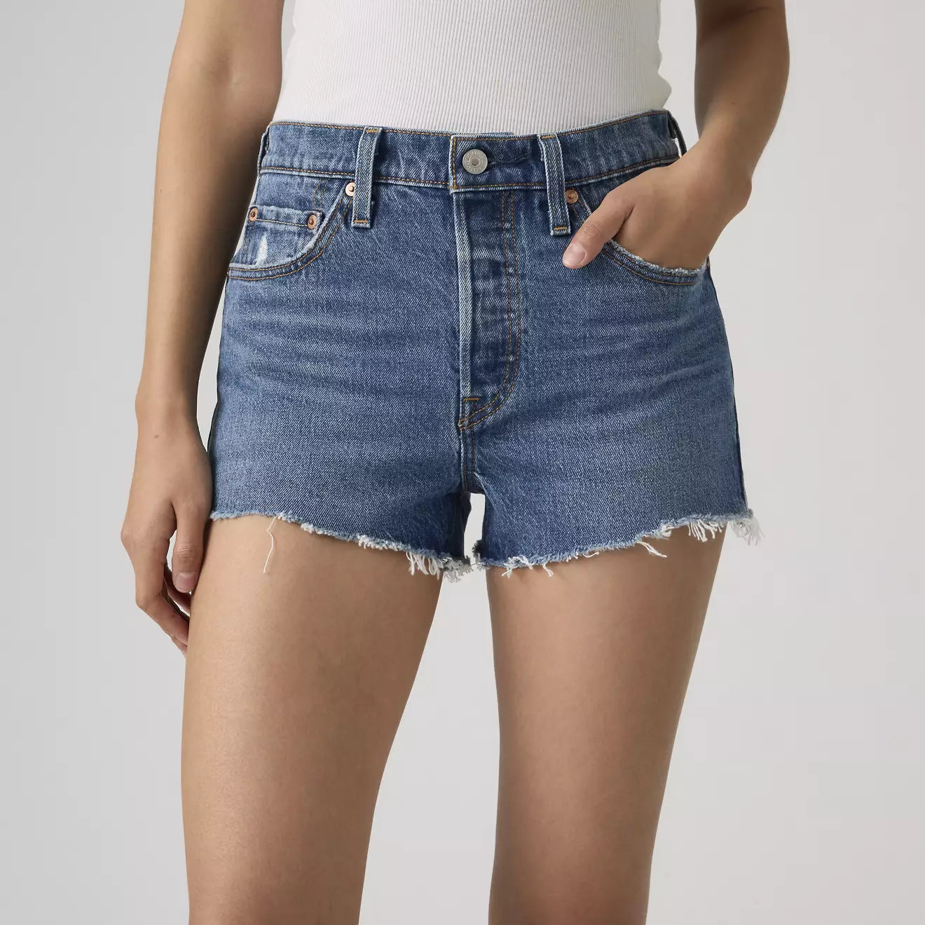 Person wearing blue denim shorts on a plain background