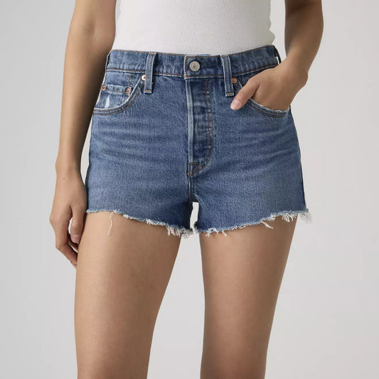 Person wearing blue denim shorts on a plain background